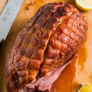 Italian pork porchetta with a golden, crispy crust, resting on a wooden cutting board. The skin is perfectly crackled, and the juicy meat inside is infused with rosemary, garlic, and fennel.