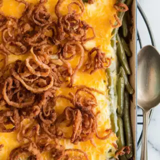 A photo of a golden, bubbling green bean casserole in a 9x13 dish, topped with crispy fried onions, fresh out of the oven. The dish sits on a trivet over a marble surface. A spoon rests beside it, ready to serve. The edges of the dish are slightly charred, showing the heat of the oven. The green beans are visible through the cheese layer, and the fried onions have a brown, crispy texture.
