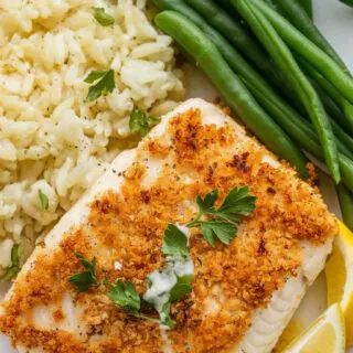 Crispy panko crusted baked tilapia served with garlic butter rice and steamed green beans. The golden crust is perfectly crisp, garnished with fresh parsley and lemon wedges for a bright, fresh finish.