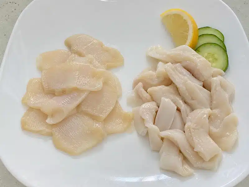 Thin geoduck siphon slices beside softer body meat pieces | EpicureDelight