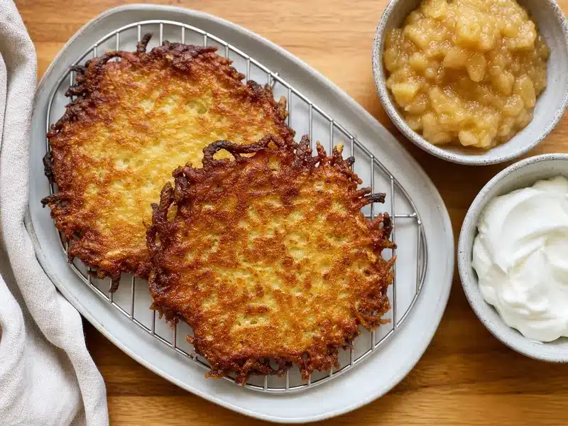 Crisp latkes with applesauce and sour cream served separately - traditional latke pairings | EpicureDelight