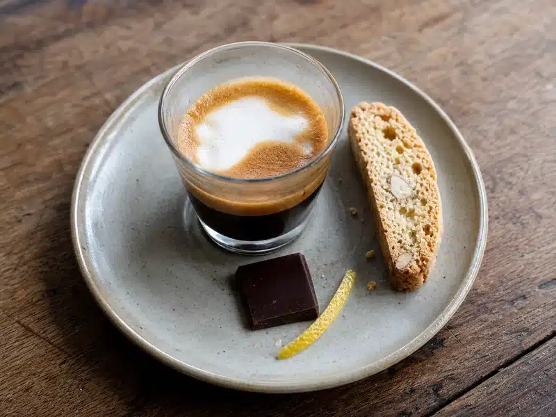 Espresso macchiato with biscotti dark chocolate and lemon peel