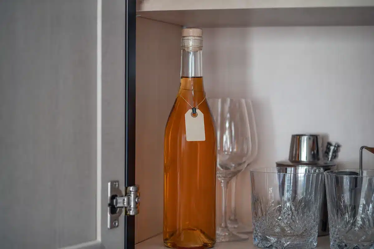 Upright peach schnapps bottle stored in a cool dark cabinet - peach liqueur storage | EpicureDelight